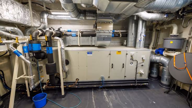 Een ruimte aan boord met daarin verschillende witte kasten en afzuiginstallaties.