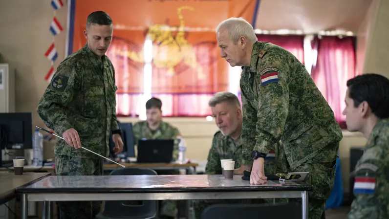 Een militair praat andere militairen bij over een training. 