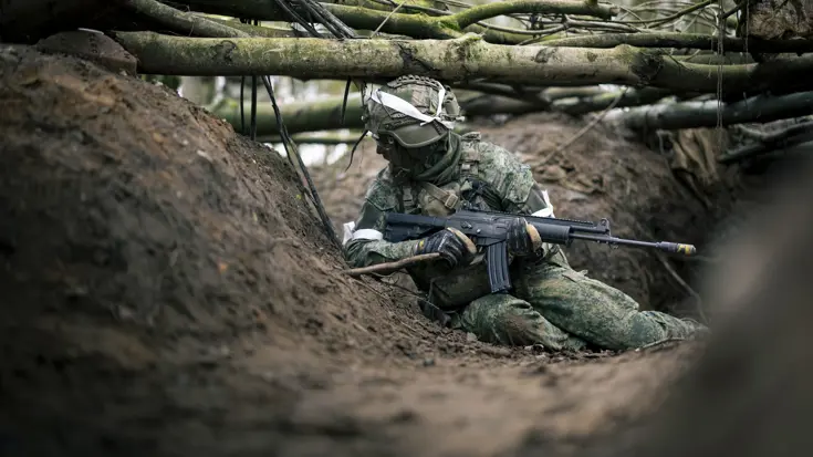 Militair in zand met wapen