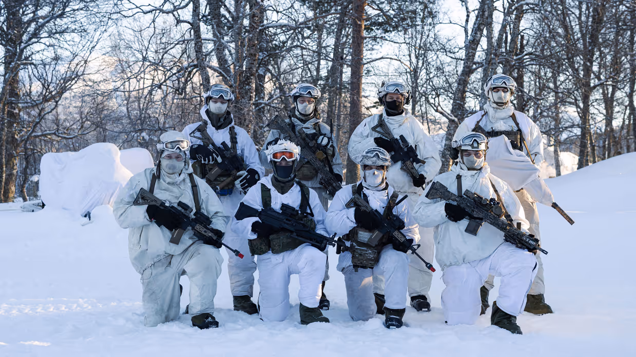 Groepsfoto van 8 gewapende mariniers in wit camo.
