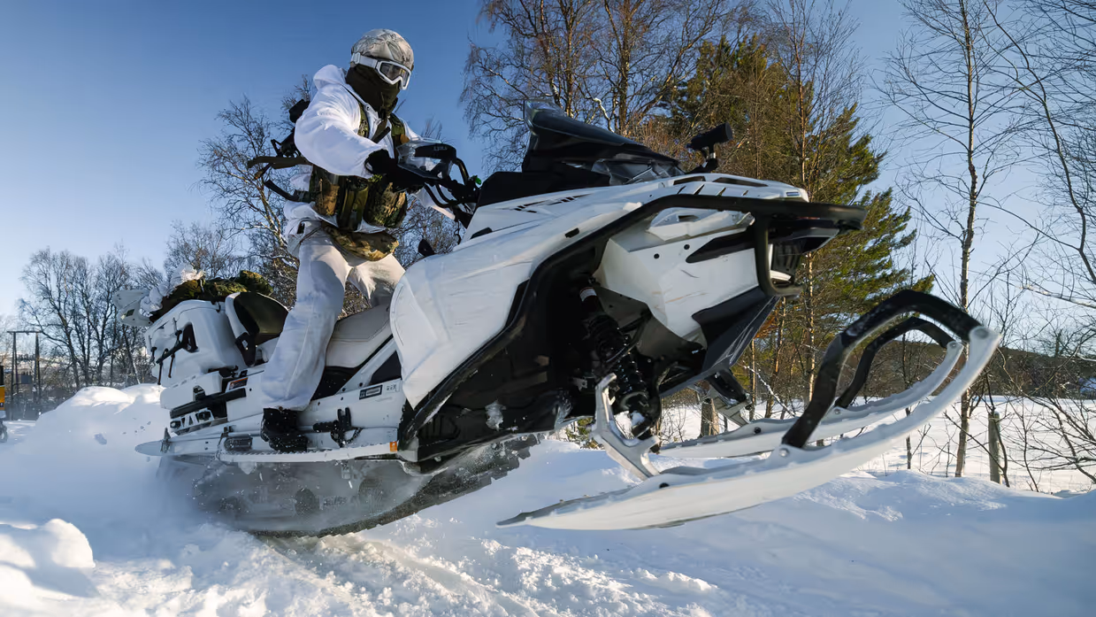 Foto links: een marinier rijdt met zijn sneeuwscooter tussen bosschages door. Foto rechts: een marinier komt met zijn sneeuwscooter los van de grond.