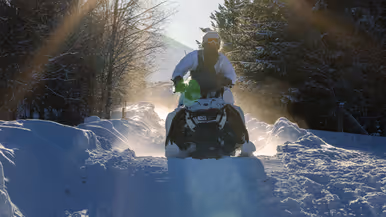 Foto links: een marinier rijdt met zijn sneeuwscooter tussen bosschages door. Foto rechts: een marinier komt met zijn sneeuwscooter los van de grond.