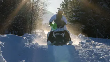 Foto links: een marinier rijdt met zijn sneeuwscooter tussen bosschages door. Foto rechts: een marinier komt met zijn sneeuwscooter los van de grond.