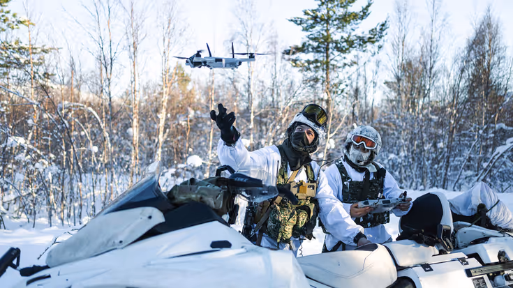 Korporaal Dani en marinier 1 Giovanni met hun sneeuwscooters in de natuur. Dani laat een drone op.