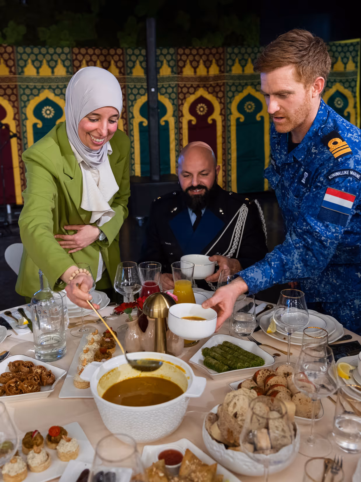 Overzicht van een tafel met eten, met mensen in uniform rondom. 