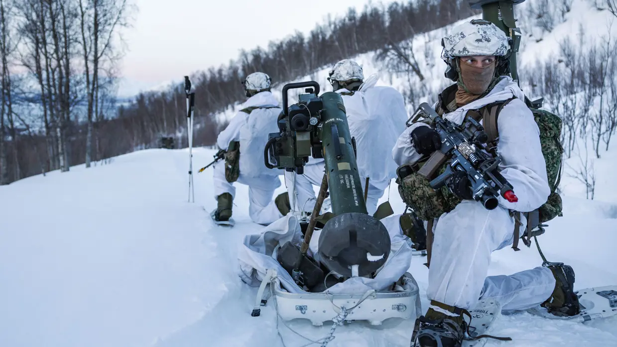 Een groepje mariniers overlegt, gehurkt in de sneeuw.