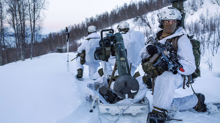 Een groepje mariniers overlegt, gehurkt in de sneeuw.