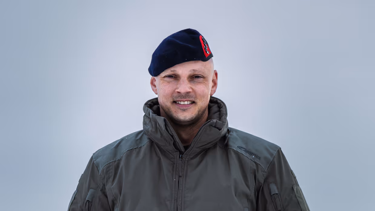 Portret van kapitein der mariniers Marnix, vlieger bij het maritieme helikoptersquadron, in winterkleding en baret staand in een besneeuwd landschap.