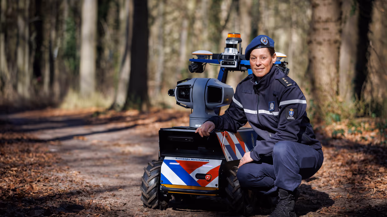 Kolonel Daisy, projectmanager innovatie bij DevOps, poseert bij de Roboguard in het bos.