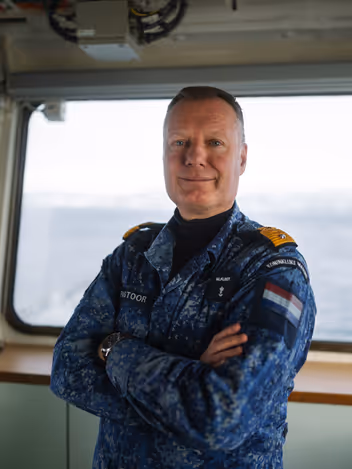 Commandeur Pastoor in boordtenue op de brug van de Johan de Witt. 