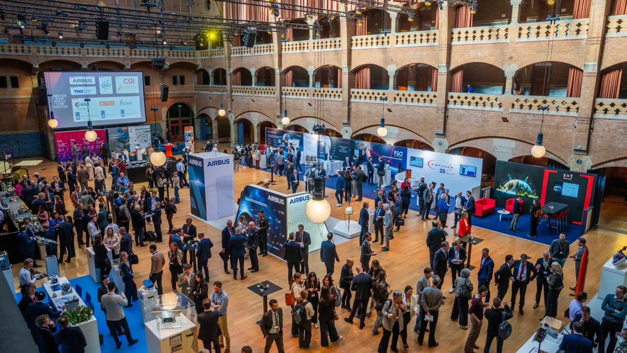 Beursvloer vol met mensen en stands van bedrijven die hun technologie laten zien. 