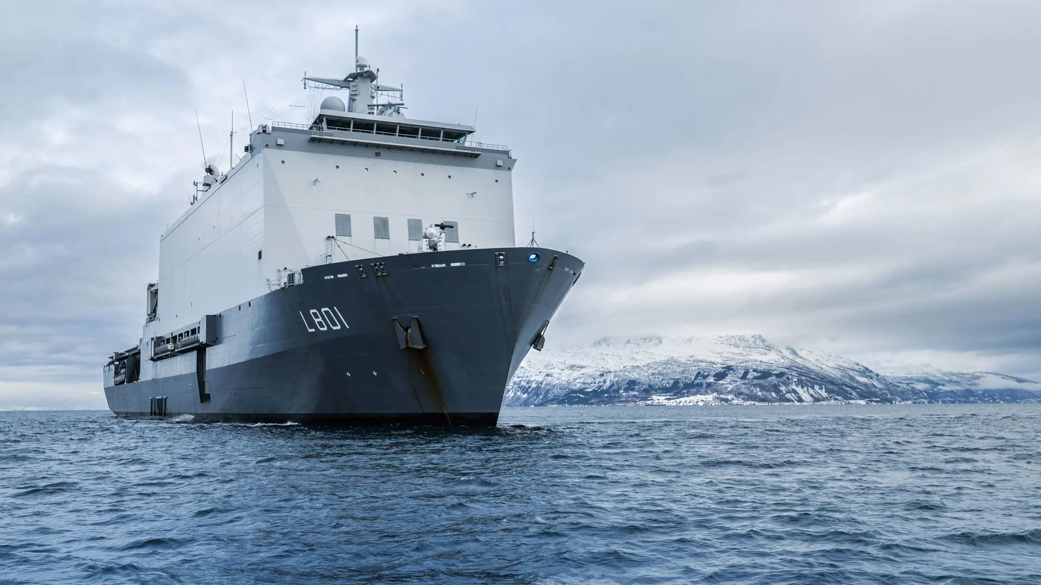 Zr.Ms. Johan de Witt vaart langs een besneeuwde Noorse kust tijdens oefening Cold Response. 
