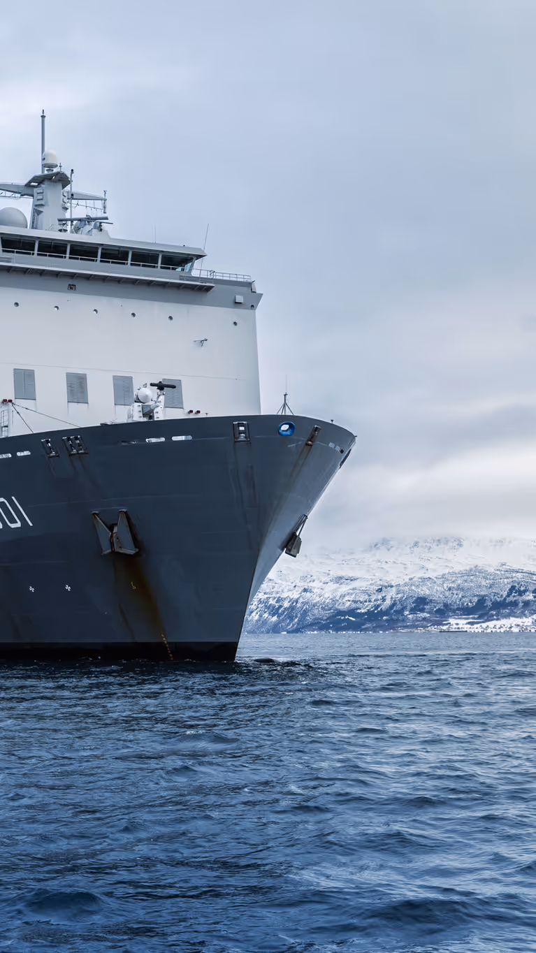 Zr.Ms. Johan de Witt vaart langs een besneeuwde Noorse kust tijdens oefening Cold Response. 