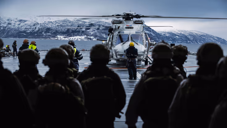 Een NH90 landt op het helidek van Zr.Ms. Johan de Witt, terwijl opvarenden toekijken. 