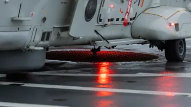 NH90-helikopter landt op het vliegdek van Zr.Ms. Johan de Witt in een Noors fjord bij schemering tijdens oefening Cold Response, terwijl dekpersoneel met lichtsignalen de landing begeleidt.