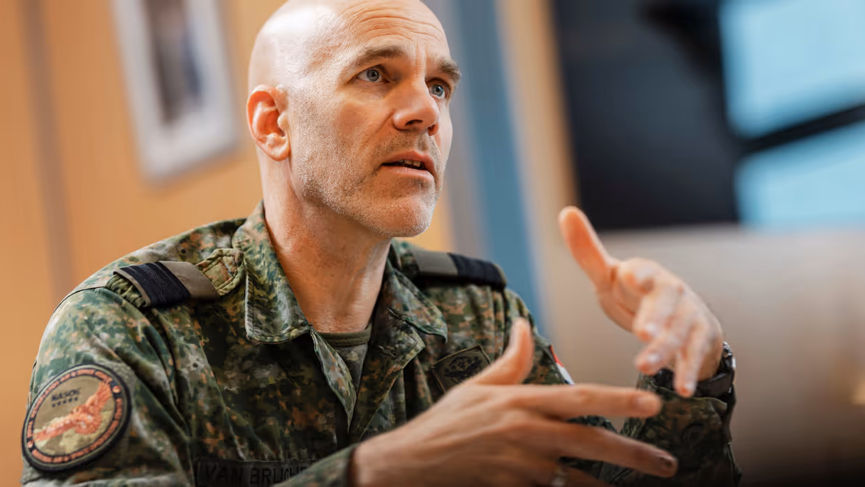 Commodore Jeroen van Bruchem zit, in militair uniform, aan een tafel en praat. Daarbij maakt hij gebruik van zijn handen.