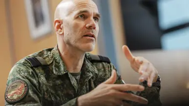 Commodore Jeroen van Bruchem zit, in militair uniform, aan een tafel en praat. Daarbij maakt hij gebruik van zijn handen.
