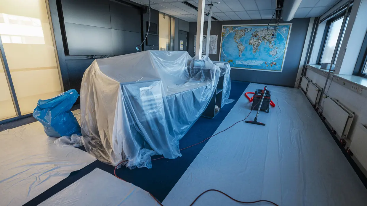 Vier foto’s van werkzaamheden. Naast een kantoorruimte met afgedekte bureaus, laptops en toetsenborden gaat het om een kabel die uit het plafond hangt. Tot slot het logo van de luchtmacht tegen een muur, daarnaast een afgedekt beeldscherm.