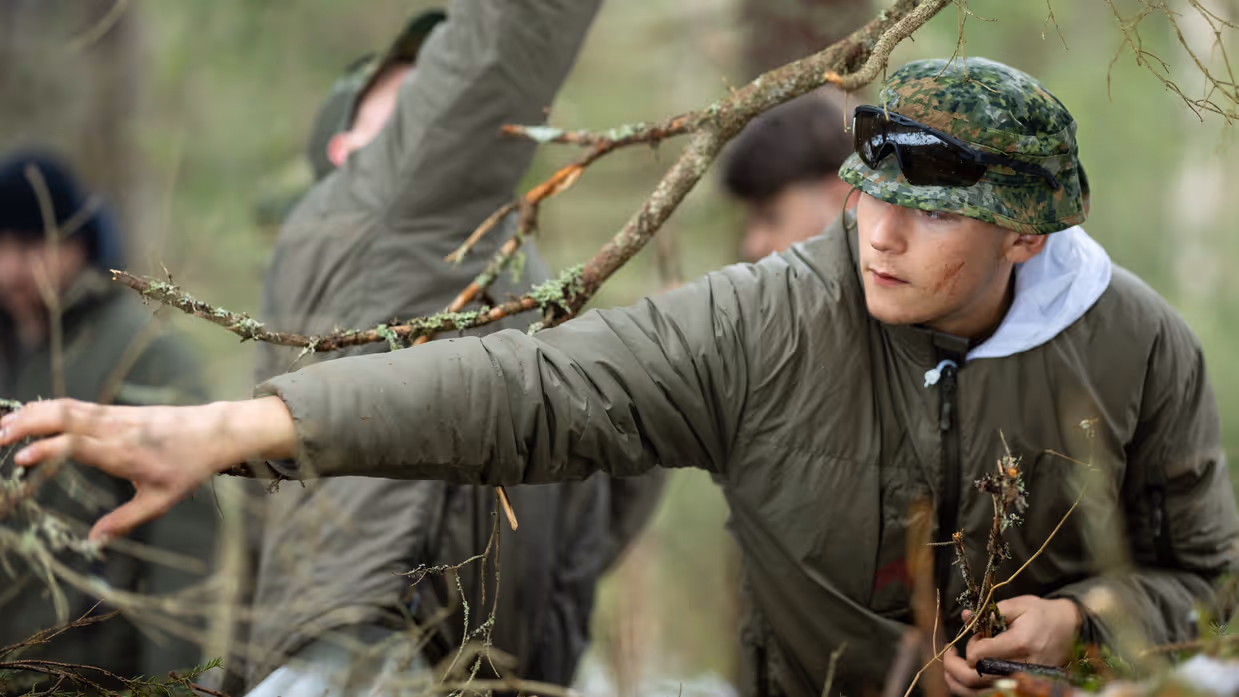 Soldaat Nathan sprokkelt in het bos brandbaar materiaal voor een vuurtje. 