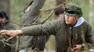 Soldaat Nathan sprokkelt in het bos brandbaar materiaal voor een vuurtje. 
