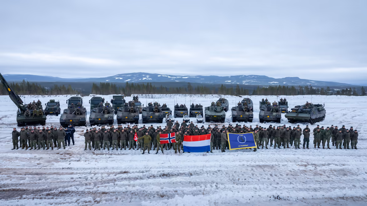 Groepsfoto van de Charlie-compagnie en de Noorse instructeurs voor alle voertuigen in een winters landschap.