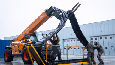 Links: een versleten rubberen band track, rechts: met een heftruck wordt een rubberen band track omhoog gehesen.