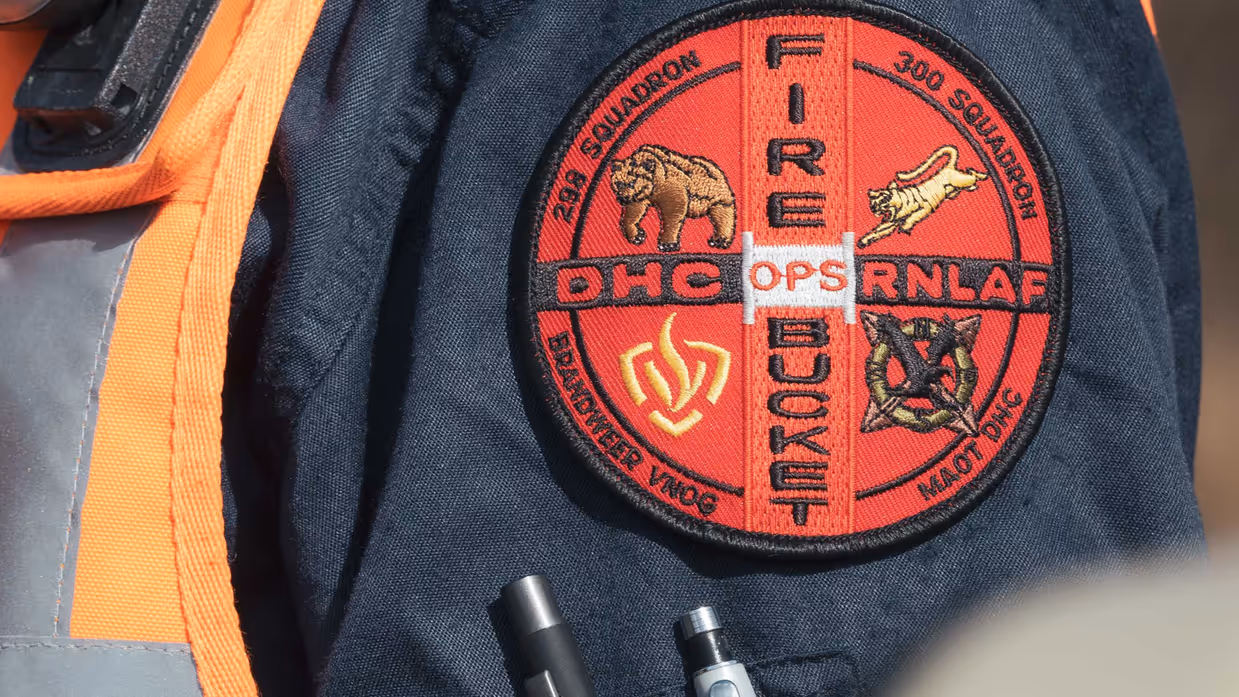 En badge op de mouw van een brandweerman met onder meer de tekst ‘DHC RNLAF – Fire Bucket Ops’.