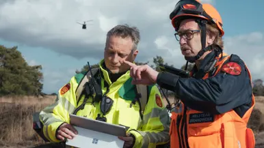 Een brandweerman (links) en een lid het heli-team van de brandweer overleggen.