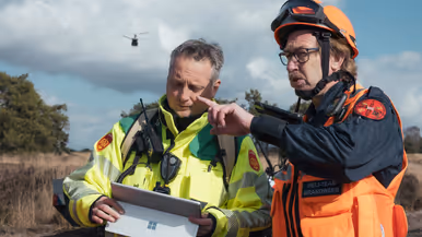 Een brandweerman (links) en een lid het heli-team van de brandweer overleggen.