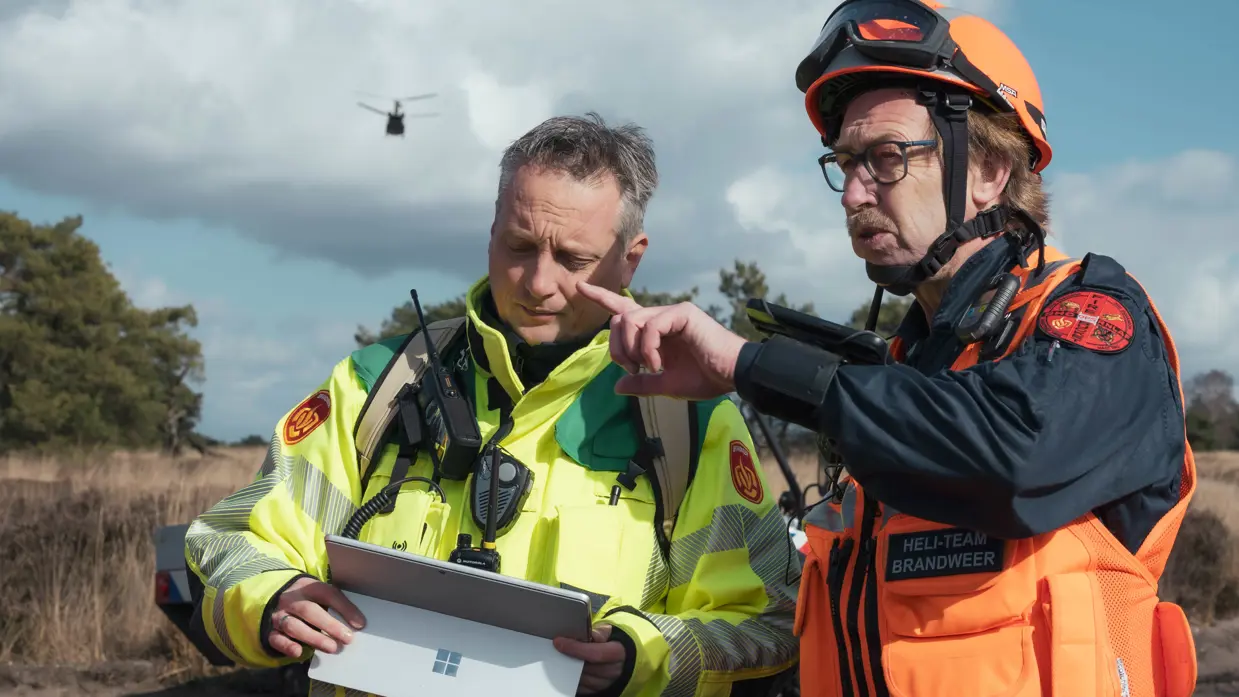 Een brandweerman (links) en een lid het heli-team van de brandweer overleggen.