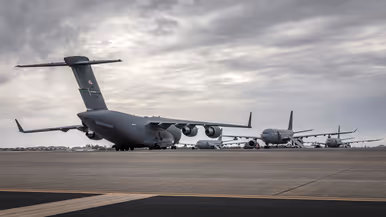 Op een groot platform staat een C-17 transportvliegtuig met de staart naar de camera. In de achtergrond zijn drie A330 MRTT’s te zien