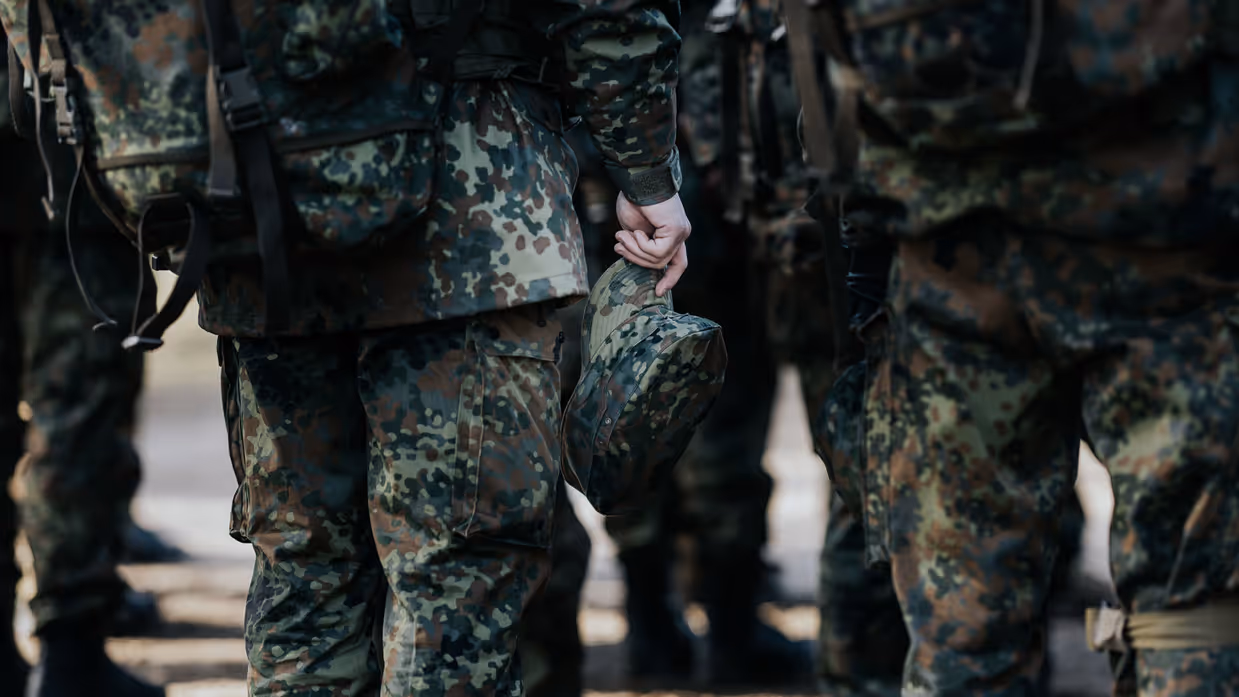 Een militair houdt zijn pet in de hand. 