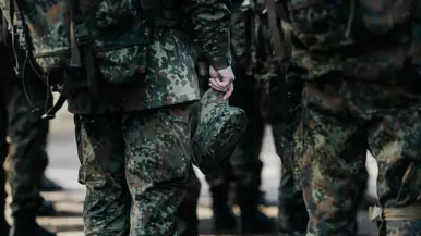 Een militair houdt zijn pet in de hand. 