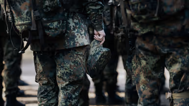 Een militair houdt zijn pet in de hand. 