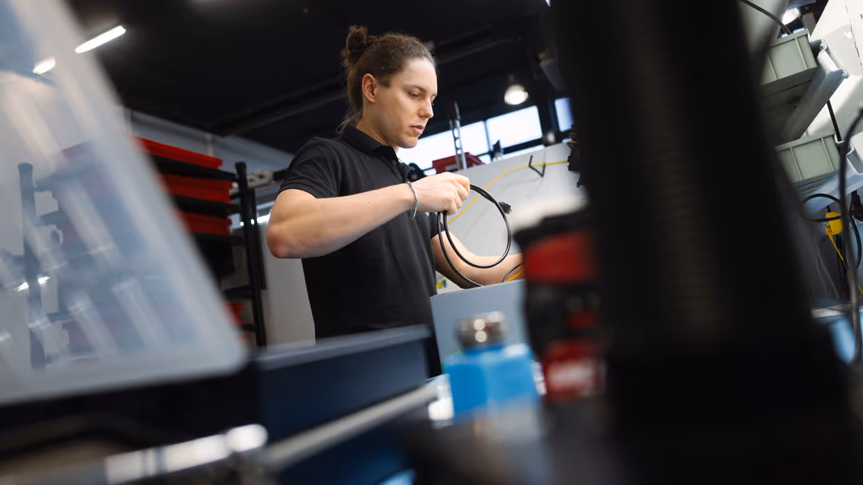 Een kijkje op het gezicht van een medewerker van Robin Radar die een kabel vasthoudt. 