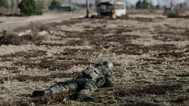 Militair ligt in schiethouding op de grond. 