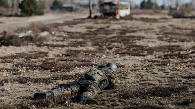 Militair ligt in schiethouding op de grond. 