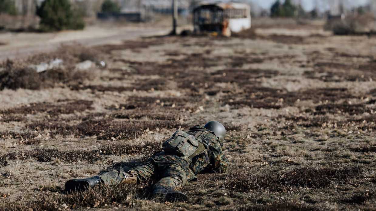 Militair ligt in schiethouding op de grond. 