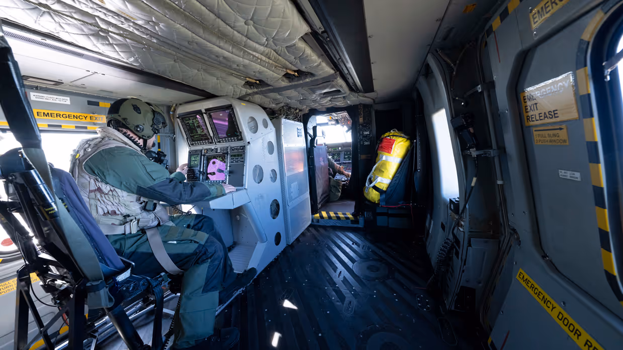 Een helicopter sensor operator zit achter zijn schermen op post in de NH90.