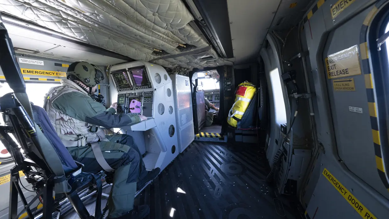 Een helicopter sensor operator zit achter zijn schermen op post in de NH90.