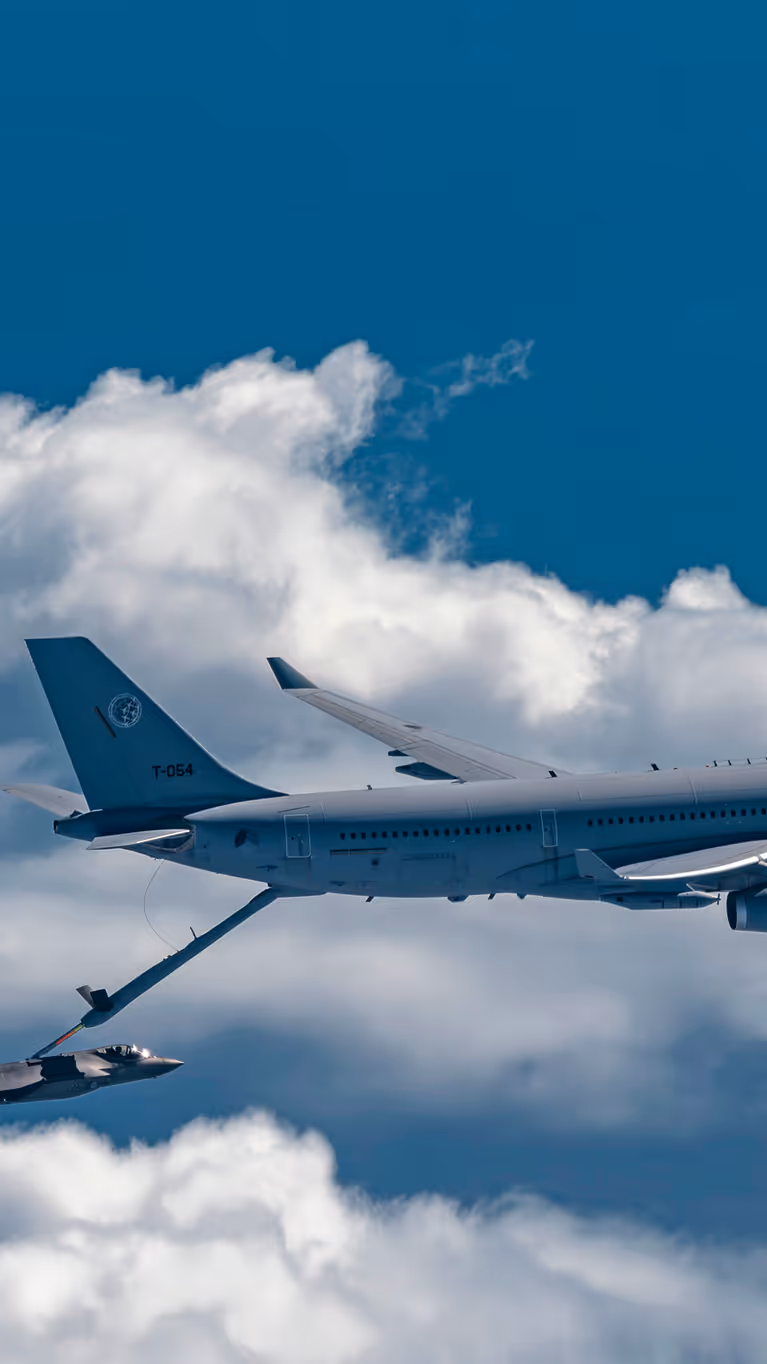 Een A330 MRTT tankt boven een wolkendek een F-35 bij.