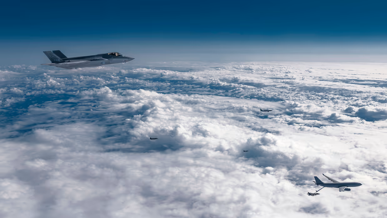 Boven een wolkendek vliegt een formatie van twee A330 MRTT’s en vier F-35’s waarvan er een getankt wordt.
