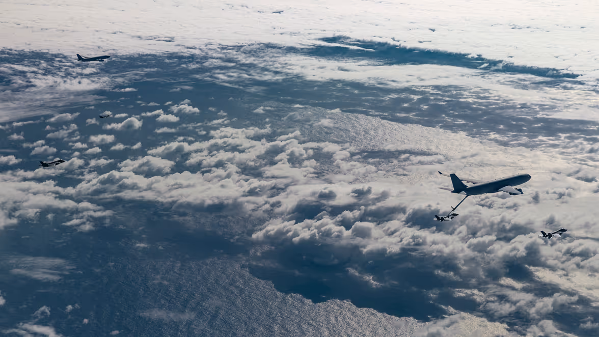 Een formatie met 2 A330 MRTT’s en 4 F-35’s, vliegend boven een bont wolkendek. 