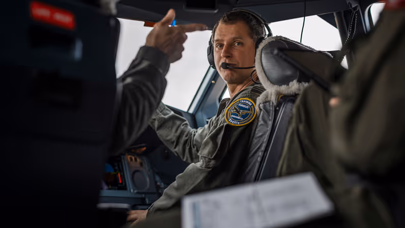 Een vlieger zit in de cockpit van de A330 MRTT en kijkt over zijn schouder achterom.