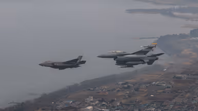 Een Nederlandse F-35 vliegt links van een Amerikaanse F-16.