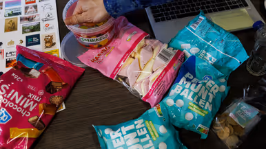 Snoepgoed en andere etenswaren op een tafel met een hand die wat winegums pakt