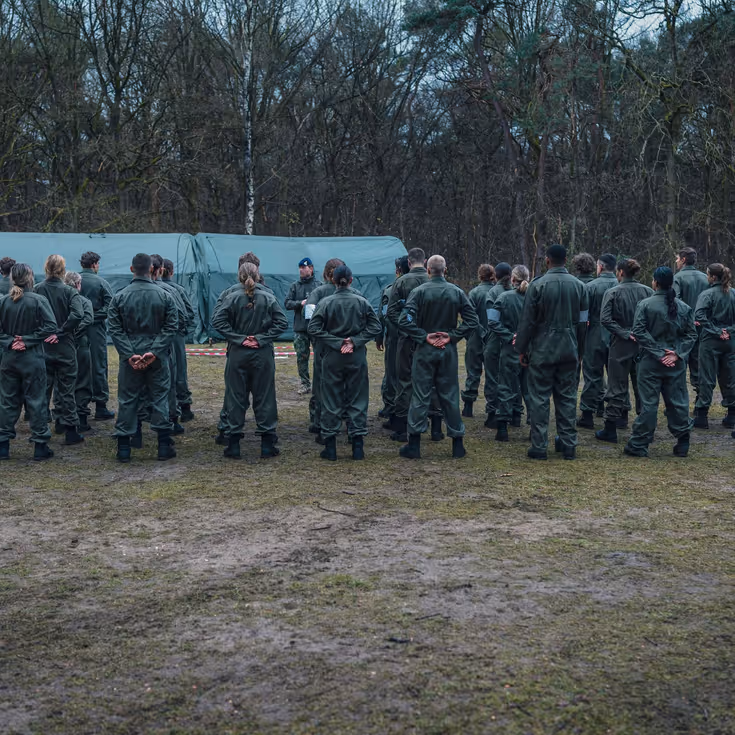 Militairen staan gegroepeerd in het bos voor een tent.