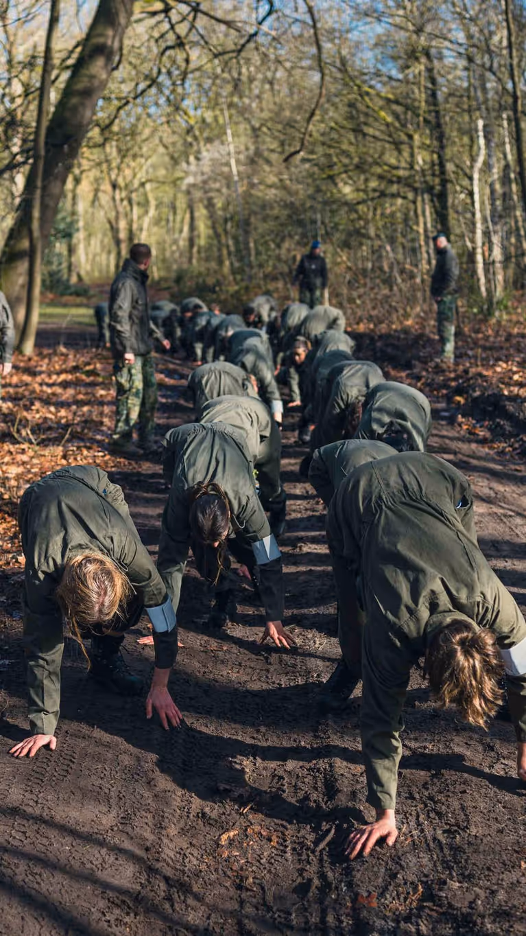 Militairen tijgeren onder begeleiding over een bospad.