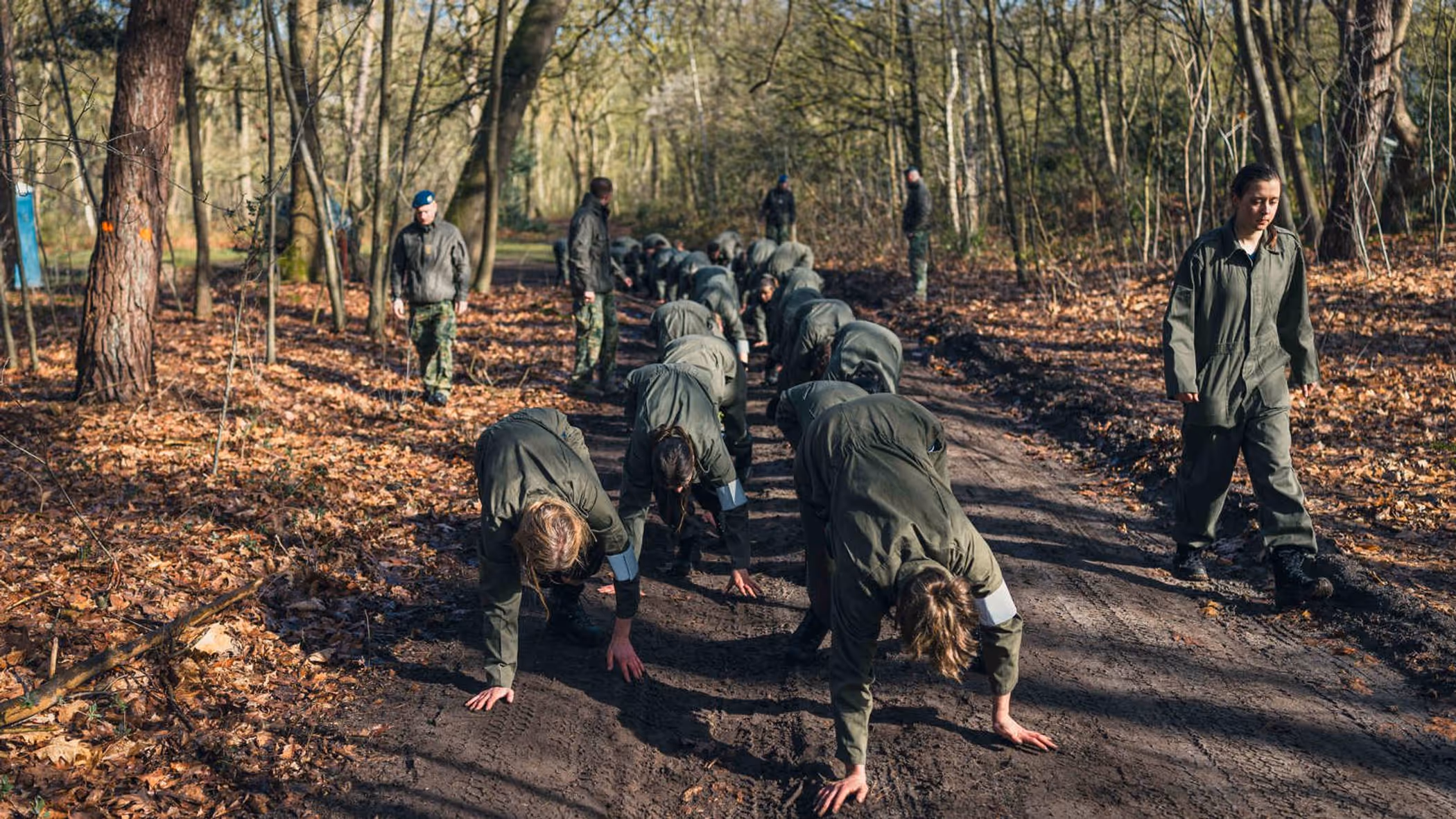 Militairen tijgeren onder begeleiding over een bospad.