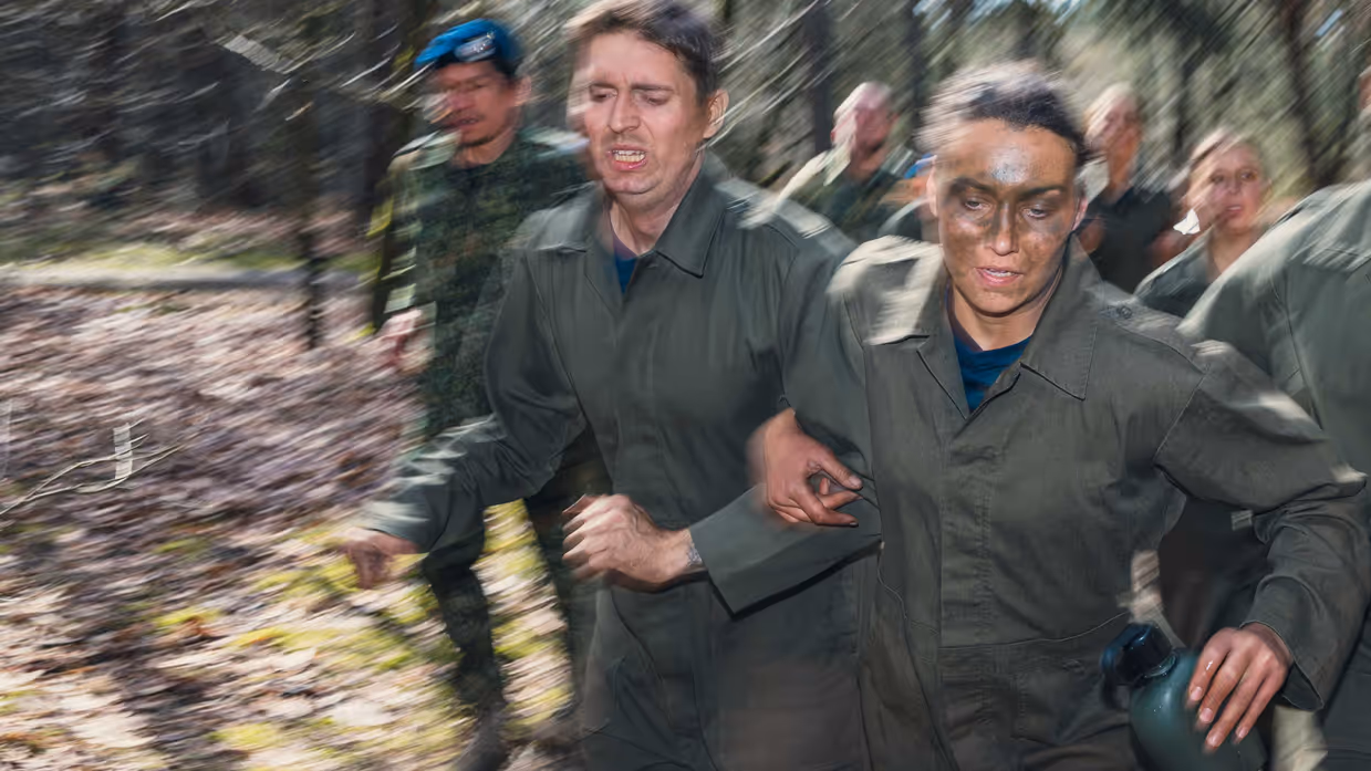 Een groepje cadetten rent met een waterfles in de hand door het bos.